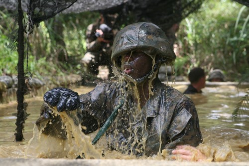 A Marine splashes as he makes his way through an obstacle course at the Jungle Warfare Training Center on Camp Gonsalves, Okinawa, Japan, Aug. 21. Marines with Marine Wing Support Squadron 172, 7th Communication Battalion, III Marine Expeditionary Force Combat Camera and the Provost Marshal Office are training at the center to become effective fighters in a jungle environment. (Photo by Sgt. Leon M. Branchaud)