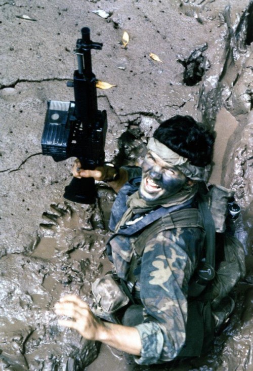Navy “SEAL” (Sea-Air-Land) Team Member moves through deep mud as he makes his way ashore from a boat, during a combat operation in South Vietnam in 1970. His gun is a Mk23 5.56mm Machine Gun (Stoner 63). Note his camouflage uniform & face paint. Photographed by PHC A. Hill.